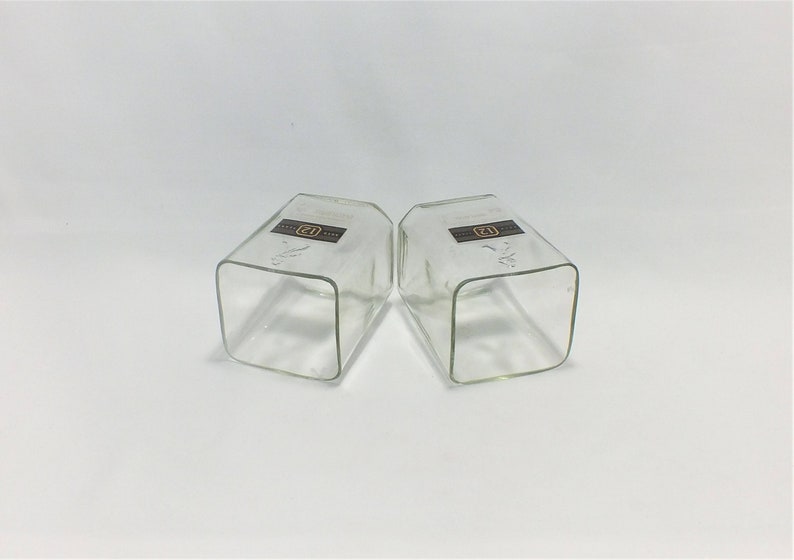 May include: Two clear glass square tumblers with a brown label that says "Old Forester" on each.