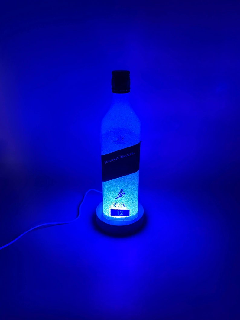 Pode incluir: Uma luz LED azul em forma de garrafa de whisky Johnnie Walker de 12 anos. A garrafa &eacute; fosca e o r&oacute;tulo &eacute; vis&iacute;vel.