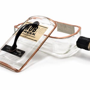 May include: A repurposed Knob Creek bourbon whiskey bottle, transformed into a decorative serving tray. The clear glass bottle features a copper-colored metal frame, a black handle, and the original label. The bottle's cap is black.