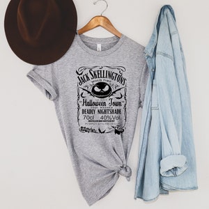 May include: A gray t-shirt with a black graphic design featuring the text "Jack Skellington's Mold Time" and "Halloween Town." The design includes a Jack Skellington face and the words "Deadly Nightshade" and "70cl 40%Vol."
