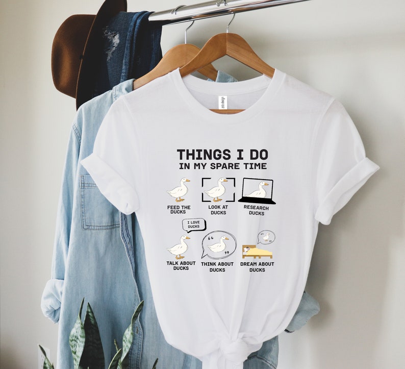 K&ouml;nnte beinhalten: Wei&szlig;es T-Shirt mit dem Text "THINGS I DO IN MY SPARE TIME" und Entenillustrationen. Das Design enth&auml;lt S&auml;tze wie "Feed the Ducks", "Look at Ducks" und "Dream about Ducks".
