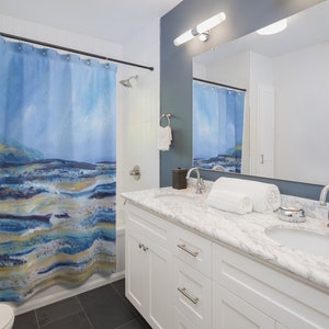 May include: A blue and white abstract art shower curtain with a landscape design. The curtain hangs in a bathroom with a white vanity, marble countertop, and a large mirror. The shower curtain has a watercolor effect.