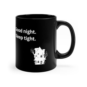 Op de afbeelding: Zwarte keramische mok met de witte tekst "Good night. Sleep tight." en een witte illustratie van een spookhuis. De mok heeft een groot, gebogen handvat.