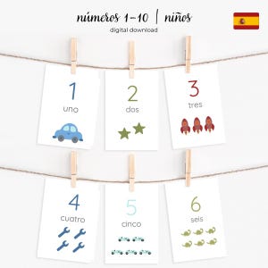 May include: A set of six cards with numbers 1-6 in Spanish, each card featuring a number, its Spanish word, and a corresponding illustration. The cards are clipped to a string with wooden clothespins. The text "números 1-10 | niños" is at the top.