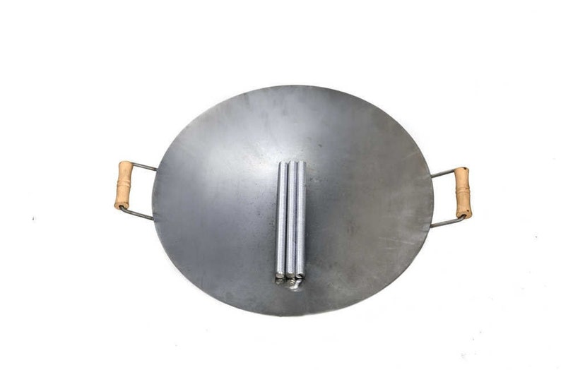 Puede incluir: Un wok grande, redondo, de color plateado con dos asas de madera. El wok est&aacute; dise&ntilde;ado para cocinar sobre fuego abierto y tiene un juego de tres patas de metal en el centro.