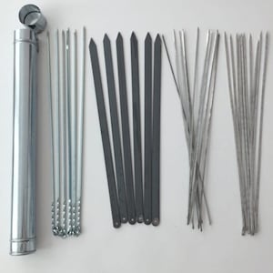 Puede incluir: Un conjunto de brochetas metálicas y un tubo de almacenamiento. Las brochetas tienen diferentes diseños, incluyendo planos, puntiagudos y retorcidos. El tubo de almacenamiento cilíndrico tiene tapa y cadena. Ideal para asar a la parrilla.