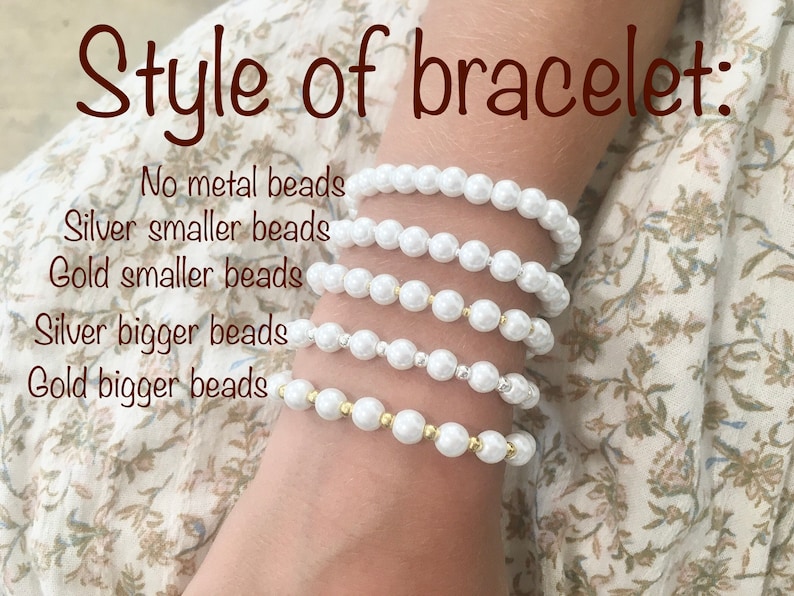 May include: Five pearl bracelets stacked on a person's wrist. The bracelets are made with white pearls and have different styles: no metal beads, silver smaller beads, gold smaller beads, silver bigger beads, and gold bigger beads.