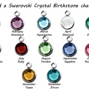 May include: A chart showing 12 Swarovski crystal birthstone charms, each with a different color and corresponding month and birthstone name. The charms are arranged in two rows of six, with the months listed below each charm.