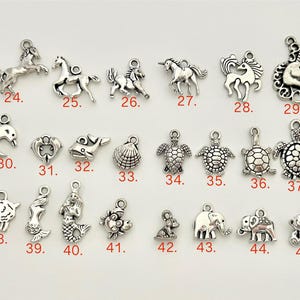 May include: A collection of 45 silver charm pendants featuring various animal and sea creature designs. The charms are arranged in rows and numbered 24 through 45.