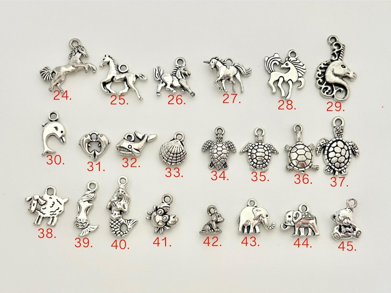 May include: A collection of 45 silver charm pendants featuring various animal and sea creature designs. The charms are arranged in rows and numbered 24 through 45.