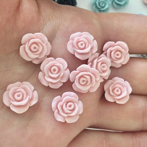May include: A collection of ten small, pink, plastic rose flower embellishments.