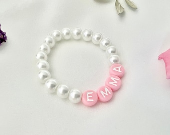 May include: A white pearl bracelet with the name "EMMA" spelled out in pink beads.