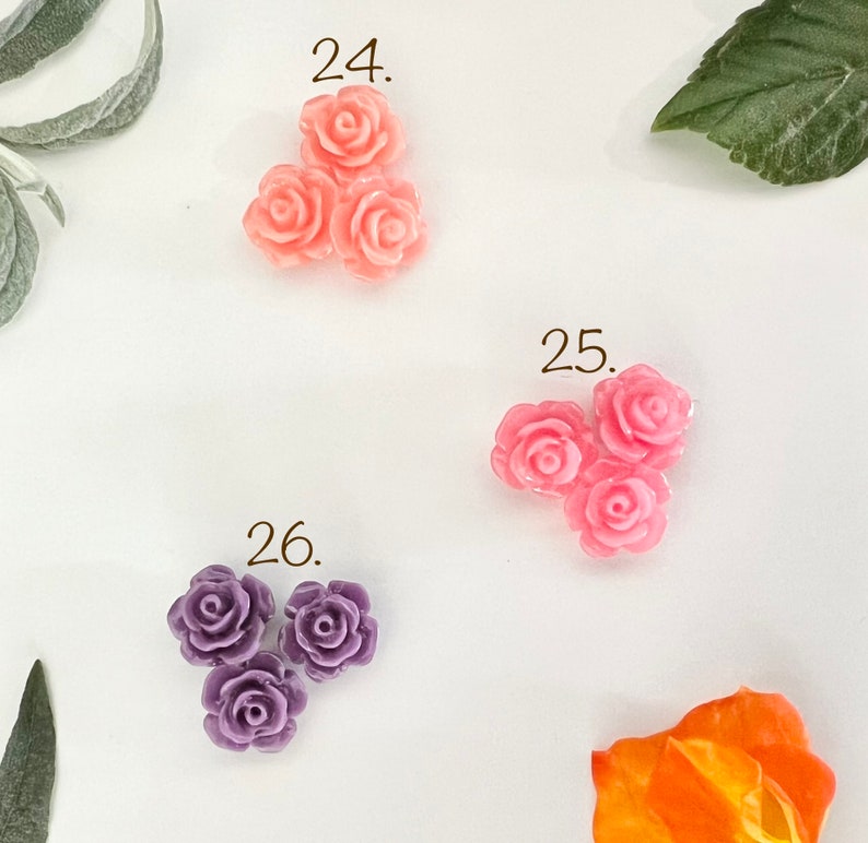May include: Three pink plastic rose flower embellishments, three pink plastic rose flower embellishments, and three purple plastic rose flower embellishments.