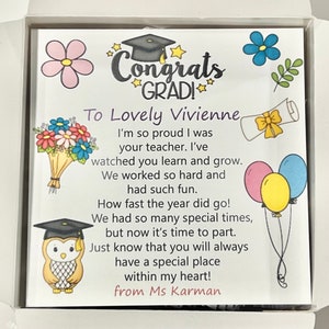May include: A graduation card with a colorful illustration of a graduation cap, flowers, and balloons. The card reads "Congrats GRAD! To Lovely Vivienne I'm so proud I was your teacher. I've watched you learn and grow. We worked so hard and had such fun. How fast the year did go! We had so many special times, but now it's time to part. Just know that you will always have a special place within my heart! from Ms Karman"