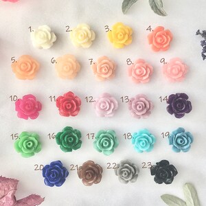 May include: Twenty-three assorted plastic flower embellishments in various colors, including pink, red, green, blue, and purple. The flowers are arranged in rows, numbered 1 through 23.
