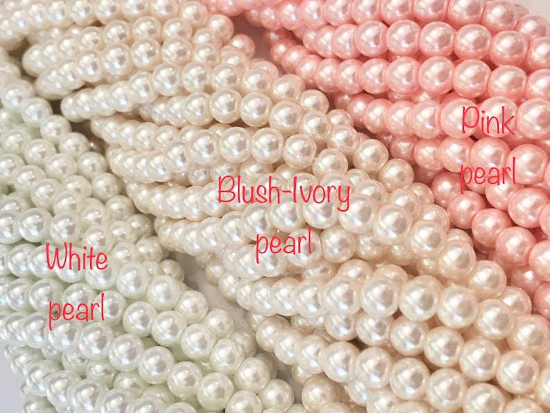 Puede incluir: Tres hebras de cuentas de perlas en blanco, marfil rosado y rosa. Las cuentas son todas del mismo tama&ntilde;o y forma, y est&aacute;n dispuestas en una l&iacute;nea horizontal.