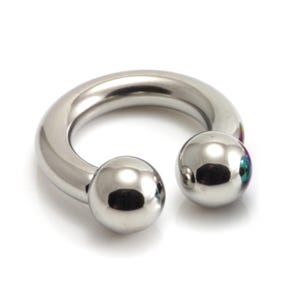 May include: A shiny, silver-colored horseshoe-shaped body piercing with two round, polished balls at the ends. The jewelry is made of a smooth, reflective metal and is set against a white background.