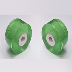 May include: Two green plastic spools with a white center hole. The spools are translucent and have a slight sheen.