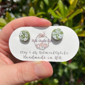 May include: A pair of green and white floral stud earrings on a white card with the text "Etsy & IG: Nelscraftylife Handmade in WI".