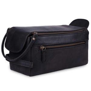 May include: Black leather travel bag with two zippered compartments and a small handle. The bag has a flap on the side and a shoulder strap. The bag is rectangular and appears to be made of a durable material.