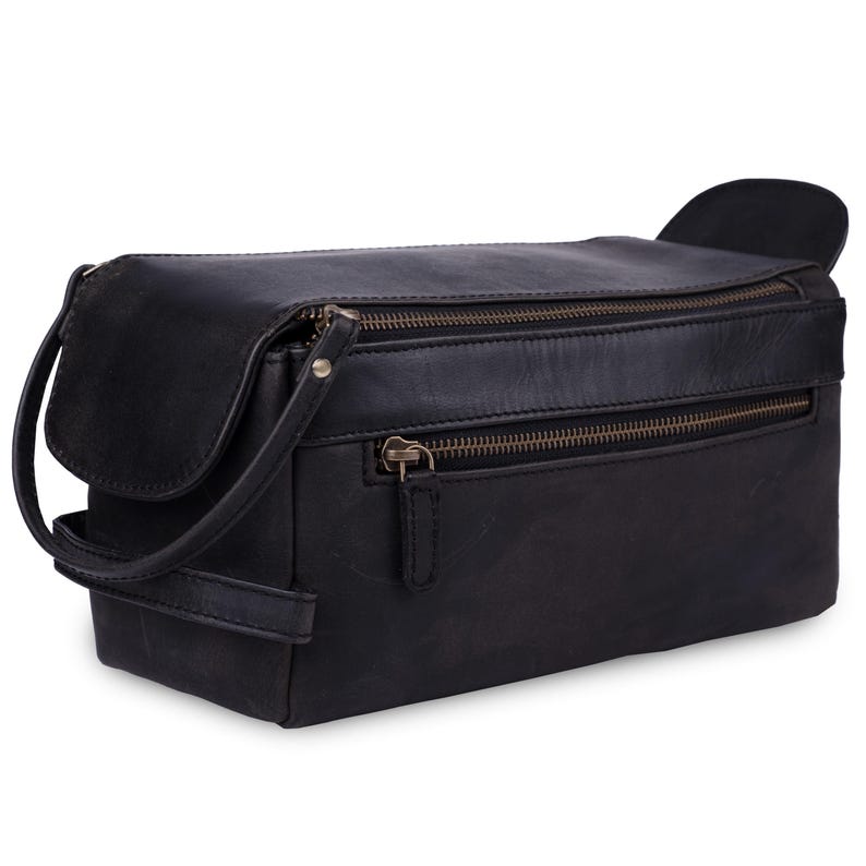 May include: Black leather travel bag with two zippered compartments and a small handle. The bag has a flap on the side and a shoulder strap. The bag is rectangular and appears to be made of a durable material.