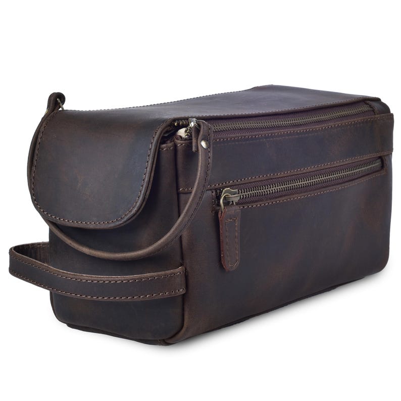 May include: A brown leather toiletry bag with multiple zippered compartments. The bag has a handle on the side and a curved flap on top. The leather has a distressed appearance.