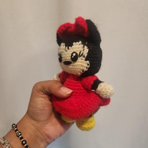 Op de afbeelding: Een handgemaakte gehaakte pop van een stripfiguur, met een rode jurk, zwart haar en een rode strik. De pop heeft gele schoenen en een cr&egrave;mekleurig gezicht en handen. De pop is ongeveer 13 cm hoog.