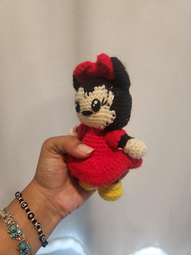 Op de afbeelding: Een handgemaakte gehaakte pop van een stripfiguur, met een rode jurk, zwart haar en een rode strik. De pop heeft gele schoenen en een cr&egrave;mekleurig gezicht en handen. De pop is ongeveer 13 cm hoog.