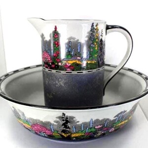 May include: A vintage ceramic pitcher and basin set. The pitcher has a black handle and a floral design with red, pink, and green accents. The basin has a matching floral border. The set is white, black, and gray.