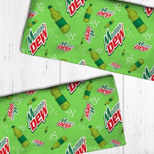 May include: Green fabric with a repeating pattern of white bubbles and the Mountain Dew logo with a green and red color scheme. The logo includes the text "Mountain Dew" and a stylized image of a bottle.
