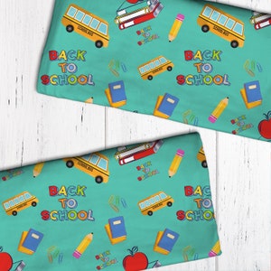 May include: A turquoise fabric with a repeating pattern of school buses, pencils, books, paper clips, and the words "Back to School".