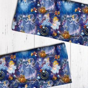 May include: A blue and purple fabric with a repeating pattern of Cinderella characters, pumpkins, and clocks. The fabric features a blue background with white stars and glitter.