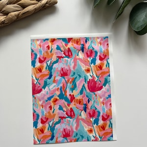 May include: A colourful floral print with pink, red, orange, and blue flowers on a white background.