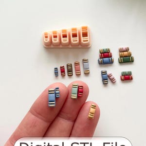 Puede incluir: Una colección de modelos de libros en miniatura en varios colores, incluyendo azul, rojo y marrón, junto con un cortador beige con forma de libro. El texto "Digital STL File" se muestra en la parte inferior. Estos artículos son probablemente para manualidades o proyectos en miniatura.