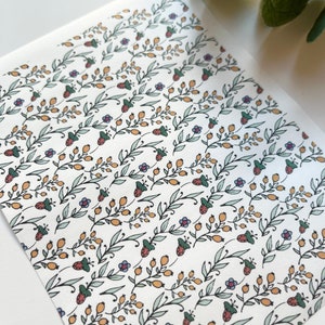 May include: A white background with a repeating pattern of small green leaves, yellow berries, and blue and red flowers.