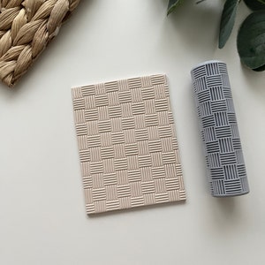 May include: A beige square coaster and a grey cylindrical roller with a woven pattern. The coaster is flat, while the roller is round. Both items have a textured surface, and are placed on a white background.