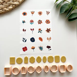 May include: A collection of floral stickers and polymer clay cutters in various shapes. The stickers feature colorful flower and leaf designs. The cutters are in geometric and organic shapes, including squares, circles, and ovals.