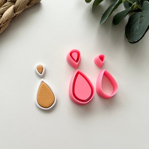 May include: A set of pink polymer clay cutters in the shape of teardrops. The cutters are used to create teardrop shapes for earrings, pendants, or other jewelry.