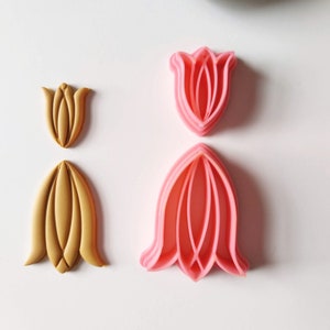 May include: Two sets of tulip-shaped cookie cutters. One set is pink and the other is gold.