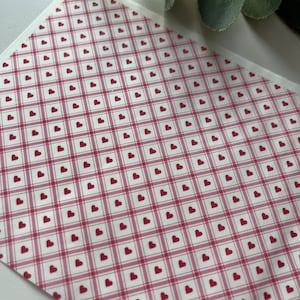May include: A white background with a red and white gingham pattern with small red hearts throughout.