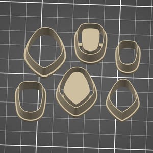 May include: Six beige cookie cutters in abstract shapes, including a teardrop, a rounded rectangle, and a modified oval. They are arranged on a dark grey grid background.