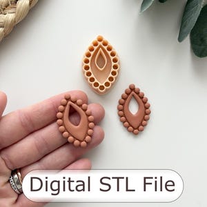 May include: Three clay earring cutters in shades of brown, one held in a hand. The cutters are teardrop-shaped with a central cutout and a beaded border. The text "Digital STL File" is displayed on a white background.