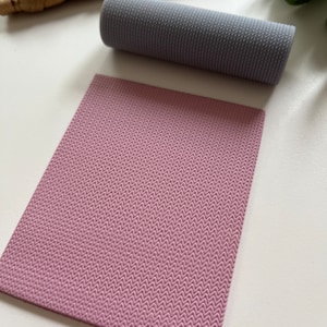 Op de afbeelding: Twee stukken textuurstof, een in lichtgrijs en de andere in lichtroze. Beide stukken hebben een visgraatpatroon.