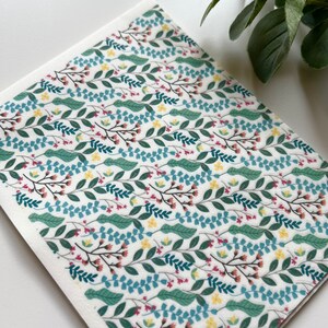 May include: A white background with a repeating pattern of green, blue, yellow, and pink floral designs. The pattern is made up of small leaves and flowers.