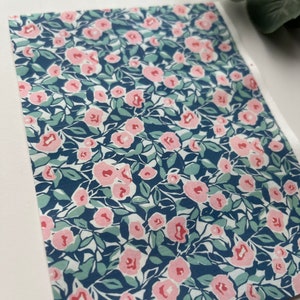 May include: A sheet of blue and white patterned paper with a repeating design of pink flowers and green leaves.