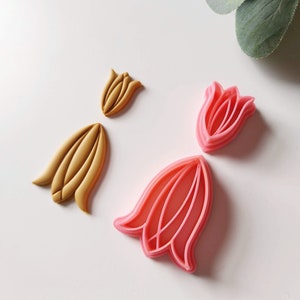May include: Two sets of flower-shaped cookie cutters. One set is pink and the other is gold.