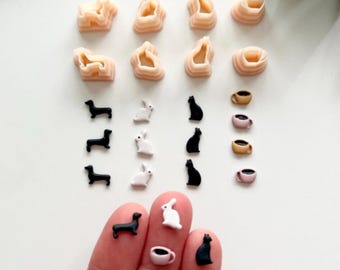 Könnte beinhalten: Eine Sammlung von Miniaturfiguren, darunter Dackel, Kaninchen, Katzen und Kaffeetassen, in Schwarz und Weiß. Es gibt auch mehrere beige, abstrakte Formen. Der Text "Digital STL File" wird in einem weißen Feld angezeigt.