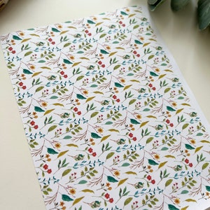 Puede incluir: Fondo blanco con un patrón repetitivo de pequeñas hojas verdes, flores rojas y flores amarillas.