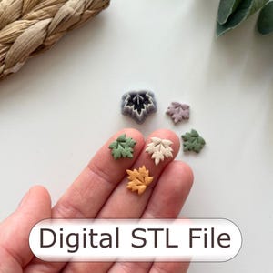 May include: Small, leaf-shaped objects in green, beige, and orange are shown. The text "Digital STL File" is visible. The leaves are arranged on a white surface, suggesting a craft or design theme. The image has a craft theme.