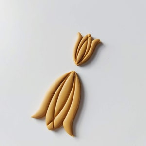 May include: Two yellow clay flower shapes, one is a closed bud and the other is an open flower.